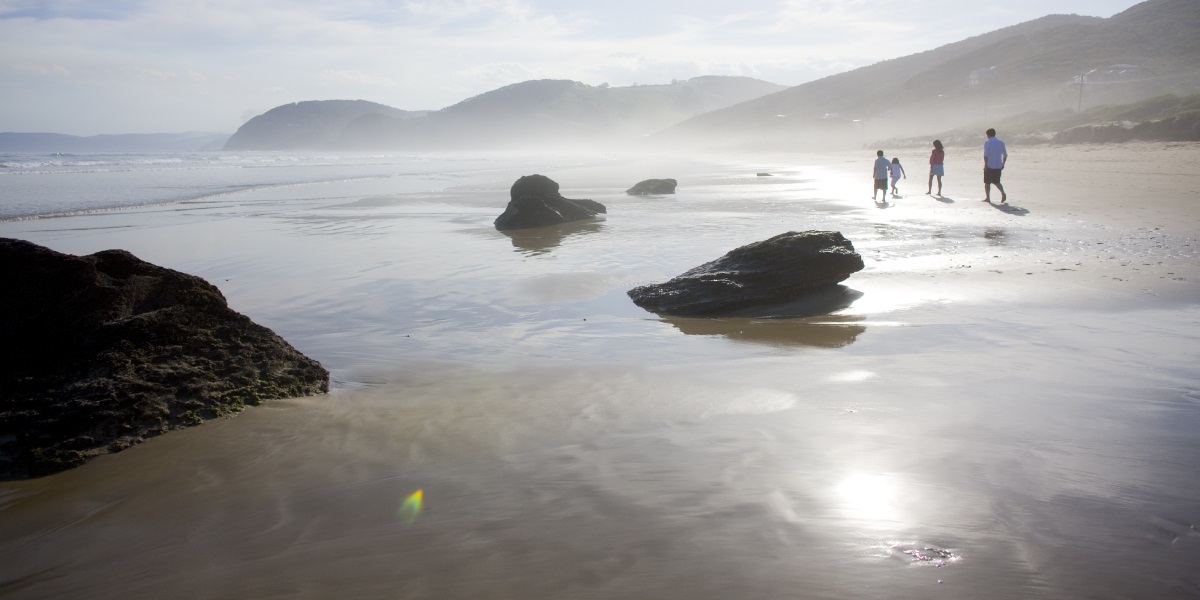 A man, woman and two children walk along the sand along Fairhaven Beach.