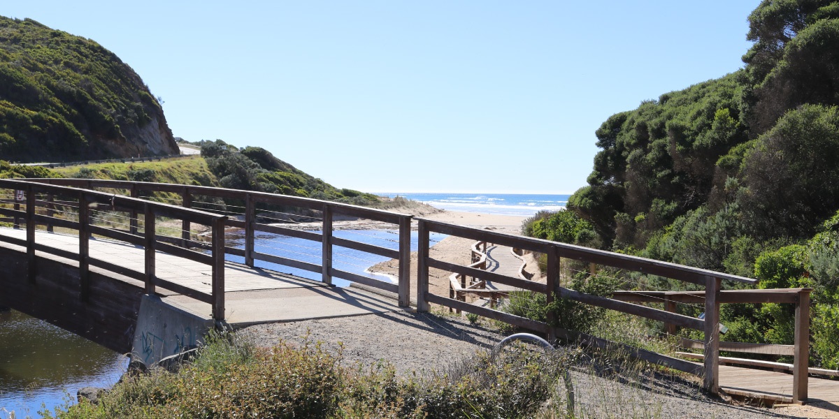 The Moggs Creek boardwalk and bridge with a view out to the ocean.