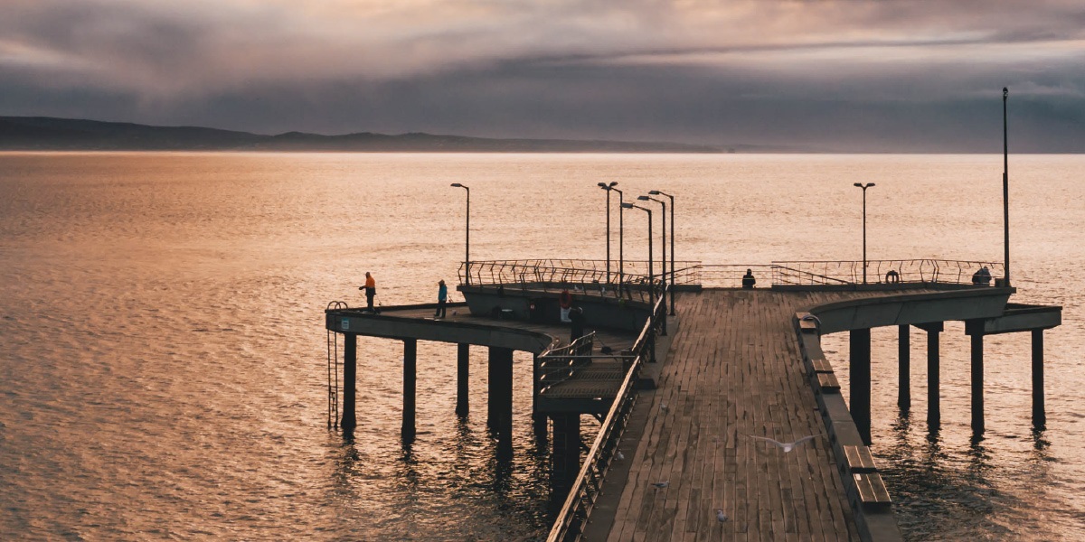 Lorne Pier at sunset, pink and orange tones in the sky, reflected on the water.