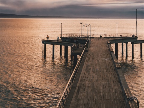 Lorne Pier at sunset, pink and orange tones in the sky, reflected on the water.